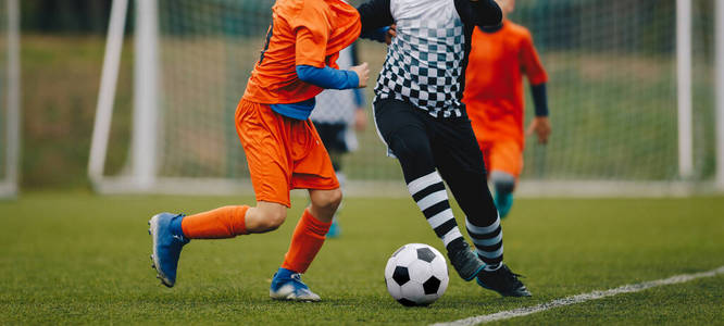 青少年足球比赛决斗。青少年足球比赛。男孩们在足球场上踢足球比赛。背景是足球场和草地
