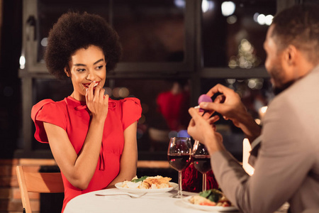 一个黑人在餐厅里展示女朋友订婚戒指求婚