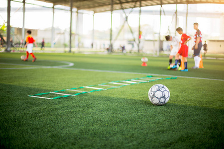 Football and Ladder Drills on green artificial turf with blurry 