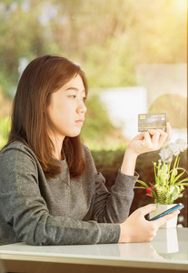 年轻女子持信用卡使用智能手机