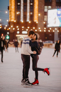 这对年轻夫妇在溜冰场溜冰并亲吻。