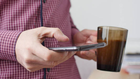 男人用智能手机发短信喝咖啡。