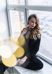 A beautiful slim blonde girl with red lips, wearing black pants 