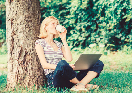为什么你应该把工作带到外面去。大自然对幸福和生产能力至关重要。女孩在公园里用笔记本电脑工作。午餐时间放松或喝咖啡休息。在夏季公园