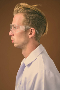 年轻英俊的医生，棕色背景下戴着护目镜