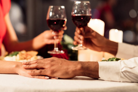 一对情侣手牵手，在餐厅里举杯庆祝情人节