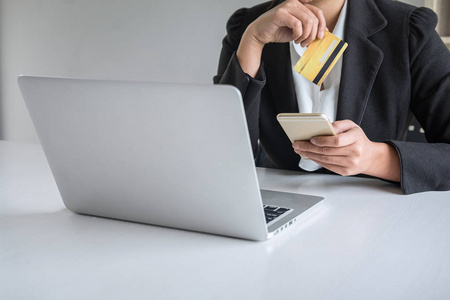 Young woman consumer holding smartphone, credit card and typing 