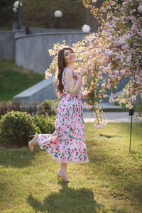 Elegant woman in beautiful dress stand by the pink tree in the p