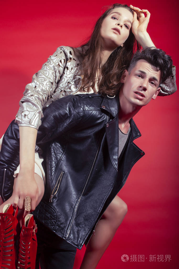 男女女在红色背景下手捧派对鞋摆造型,时尚风格让人眼前一亮照片-正版