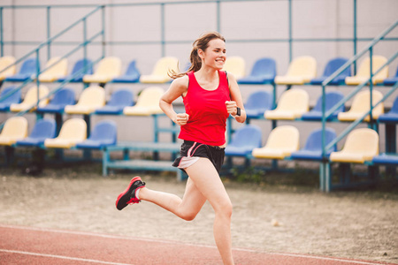 在体育场跑步的女人。年轻女子在体育场跑道上奔跑。目标实现概念。棒球场健身慢跑训练。健康主题。有氧运动训练减肥成功