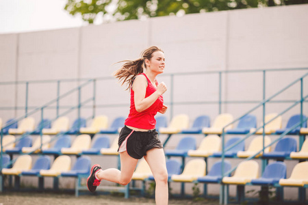 女运动员在体育场跑道上慢跑，女运动员在户外跑步和锻炼，运动和健身概念。穿着运动服在体育场训练的年轻女子。运动生活方式主题