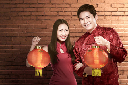 Asian Chinese couple in cheongsam dress holding Chinese lantern 