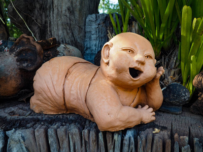 泰国工艺品,陶俑雕像,泰国新手趴在干燥的木头上,左手托着下巴.照片