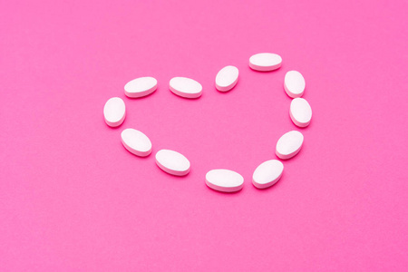 白色椭圆形药丸躺在粉红色的背景上.复制空间,宏照片