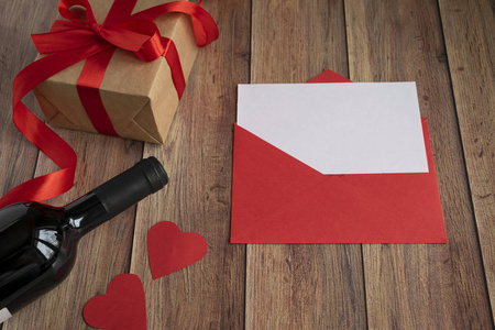 情人节的背景。一瓶酒，一份牛皮纸送的礼物，一个红包，一个心形和一条缎带