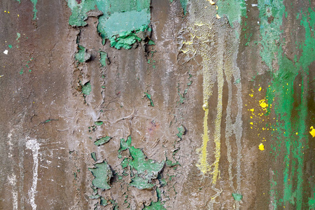 旧的生锈的金属表面覆盖着几层剥落的棕色和绿色油漆，还有一个黄色的彩弹残骸