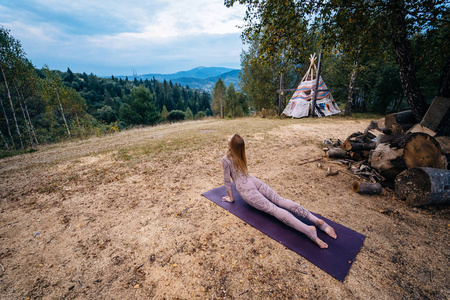 一个女人早上在一个空气清新的公园里练习瑜伽。