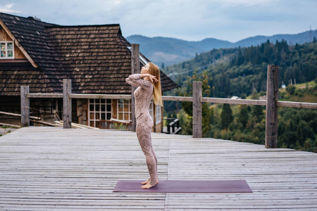 一个女人早上在一个有新鲜空气的露台上练习瑜伽。