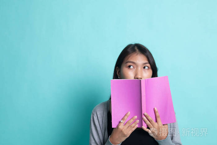 一位年轻的亚洲妇女拿着一本书遮住了她的脸