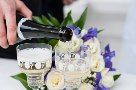 一杯香槟和新娘花束。新郎倒香槟酒杯婚礼。可用于贺卡婚礼请柬和广告服务。