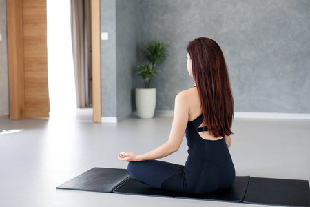 年轻女子练习瑜伽.女孩坐在屋内的垫子上打坐.体育锻炼.照片