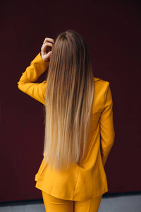 back view on woman with long hair in yellow classic suit. close 