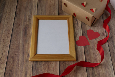 情人节背景。相框，礼物，心形和红色缎带在木制背景上。情人节，母亲节