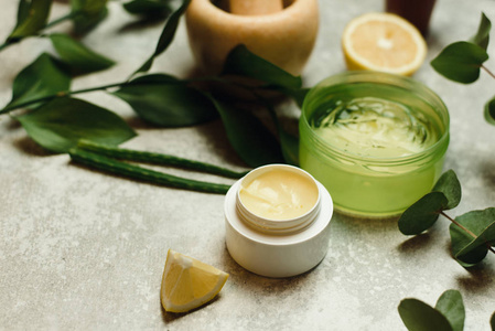 Yellow natural moisturizer in a white jar on a gray background. 