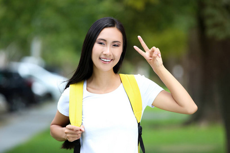 漂亮的年轻女子伸出两个手指背着背包