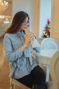 年轻美丽的亚洲女人坐在咖啡馆里闻着纸袋里的甜点