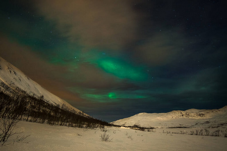 极光，极光和许多云和星星在欧洲北部山脉上空的北极光Tromso，挪威.long快门速度。