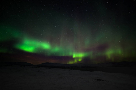 戏剧性的极光，极光与许多云和星星在欧洲北部的山脉上空的北极光瑞典阿比斯克。长快门速度。