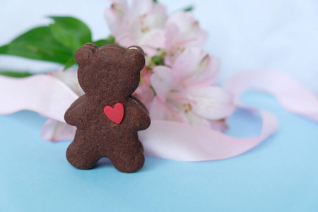 熊形状的饼干，粉红色的背景上有一条粉红色的丝带。