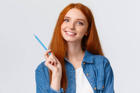 特写波特兰迷人的才华横溢的红发女孩受到启发想画画，拿着彩色铅笔，在网上学习美术，微笑着，站在白色背景下快乐