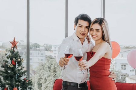 Young Asian couple celebrating new year together, drinking wine 