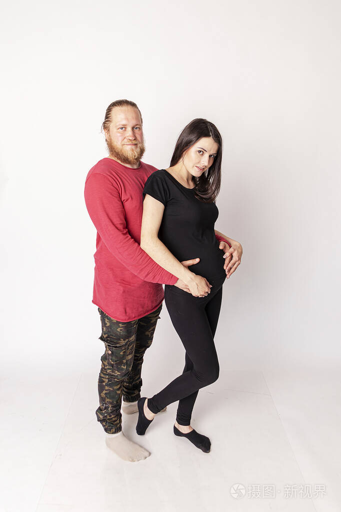 留着胡子的白人男子穿着红色毛衣拥抱怀孕的白人