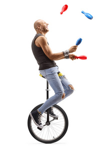 Bald man juggling and riding a unicycle 