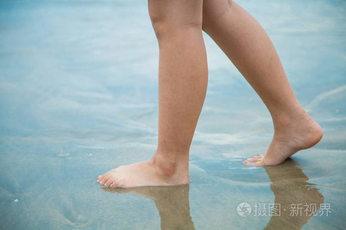 白天女人的脚在沙滩上行走去争取