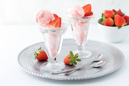 装满水果勺子近距离拍摄两个玻璃甜点盘,里面装满草莓冰淇淋,后面还有