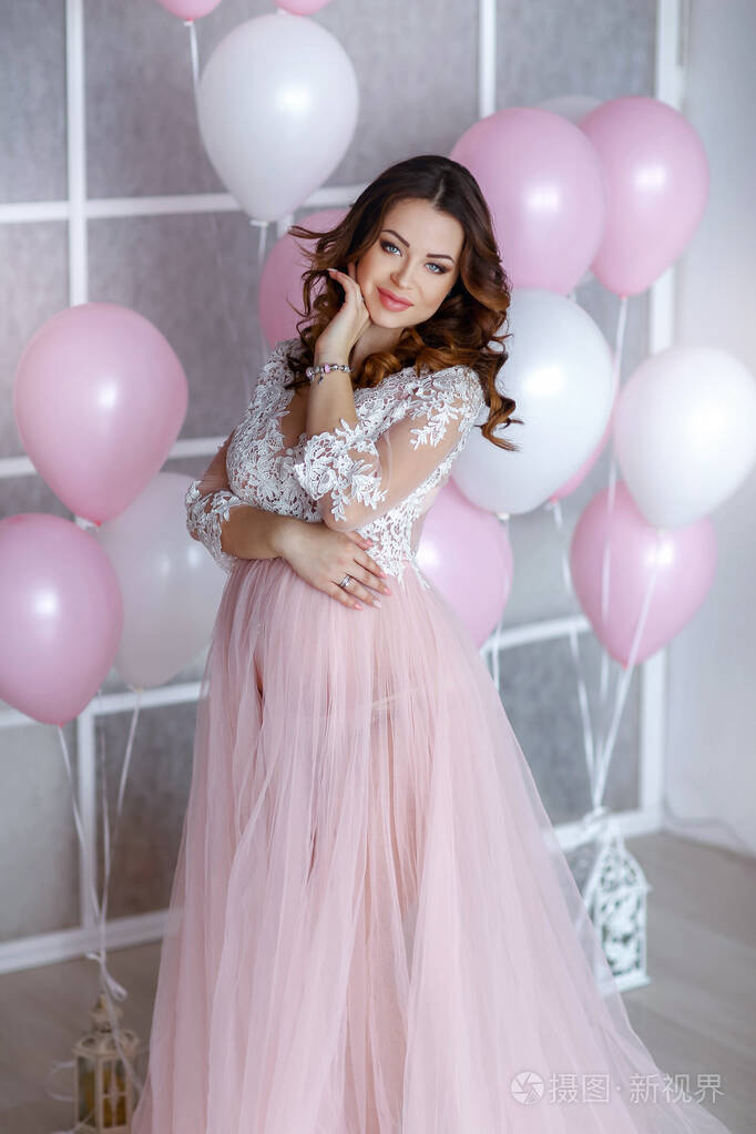 一个长发的怀孕新娘背景是粉白色的气球