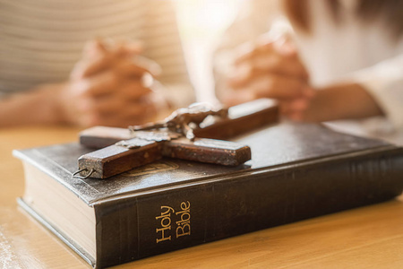 基督教妇女双手合十在圣经和木十字架上祈祷.