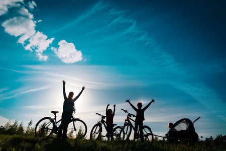 快乐的妈妈和孩子们在夕阳下骑车，一家人一起享受骑自行车的乐趣