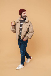 图为穿着冬装戴着帽子的男子拿着咖啡微笑