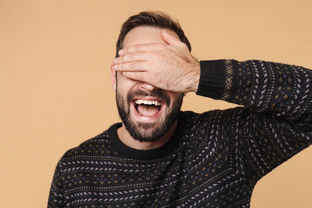 Image of happy brunette man laughing and covering his eyes with 