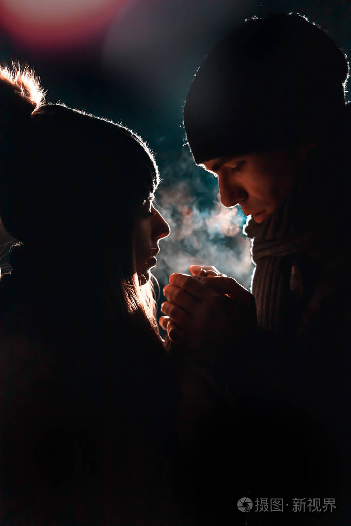 一对年轻夫妇手牵手温暖他们晚上寒冷的天气bokeh灯