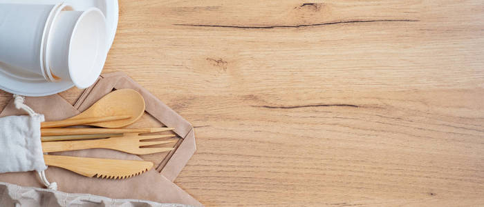竹制餐具，可生物降解纸箱纸杯和盘子放在木桌上。横幅模板与生态自然银器。零浪费，无塑料概念。可持续的生活方式