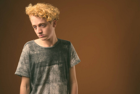 棕色背景下卷发瘦小的年轻人照片