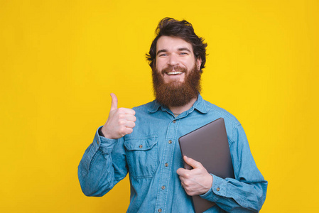 快乐工人竖起大拇指举着笔记本电脑的照片