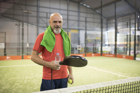 在球场上用一瓶成熟的网球拍和毛巾。