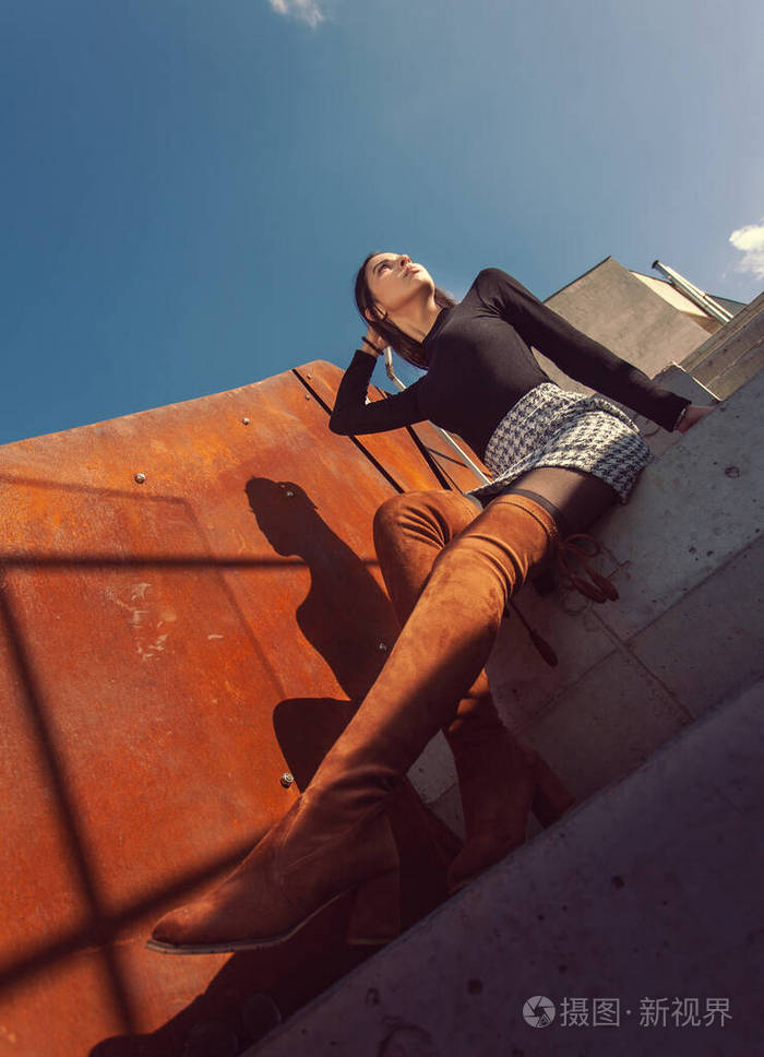 时髦的女模特坐在大楼的台阶上摆姿势